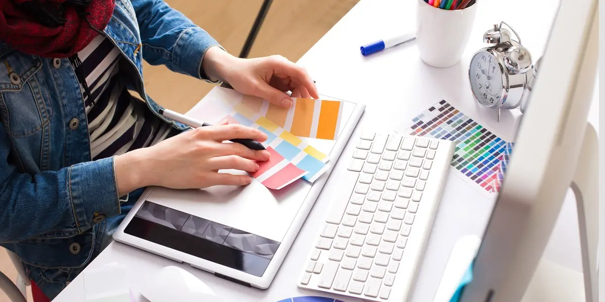 A designer sitting at a desk, looking at color swatches