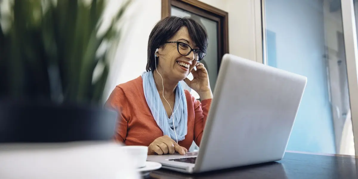 A designer wearing earbuds and sitting at a desk behind a laptop at a desk
