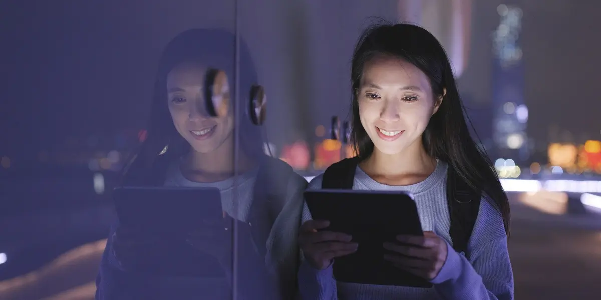 A designer standing by a whiteboard in a dark room, working on a tablet
