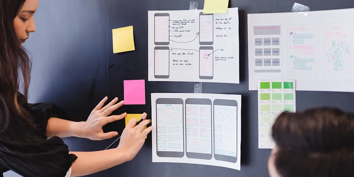 A UX designer looking at a set of wireframes on a wall