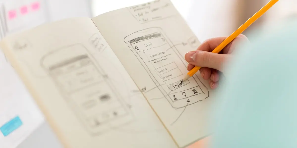 Close-up of a designer's hands, working on a paper prototype for a UX redesign