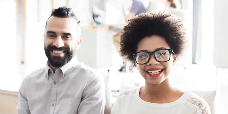 A UX designer and web developer sitting side by side, smiling at the camera