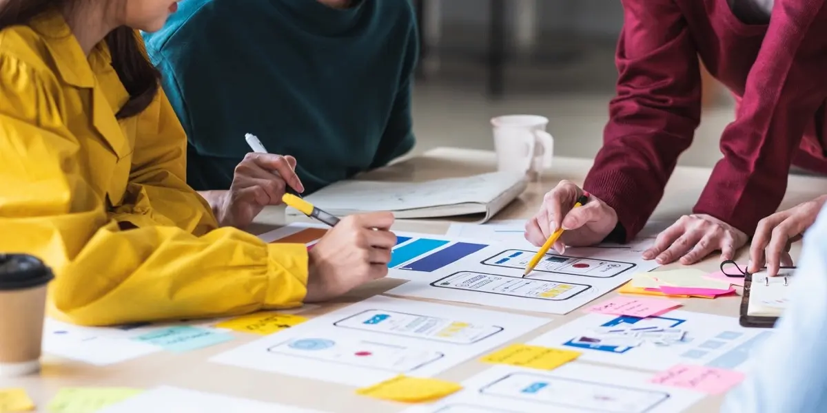 A group of designers and researchers gathered around a table, comparing research to prototypes