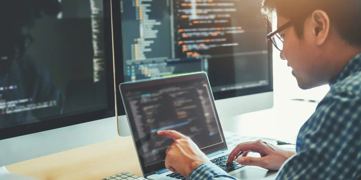A big data engineer in side profile, writing code on a laptop