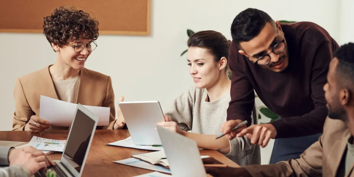 How to design for inclusion A group of designers and business people gathered around an table discussing inclusive design.