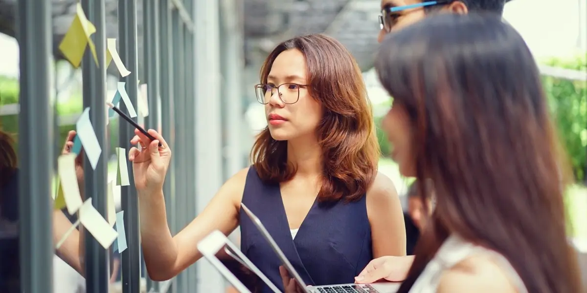 Three designers standing at a whiteboard, reviewing project details