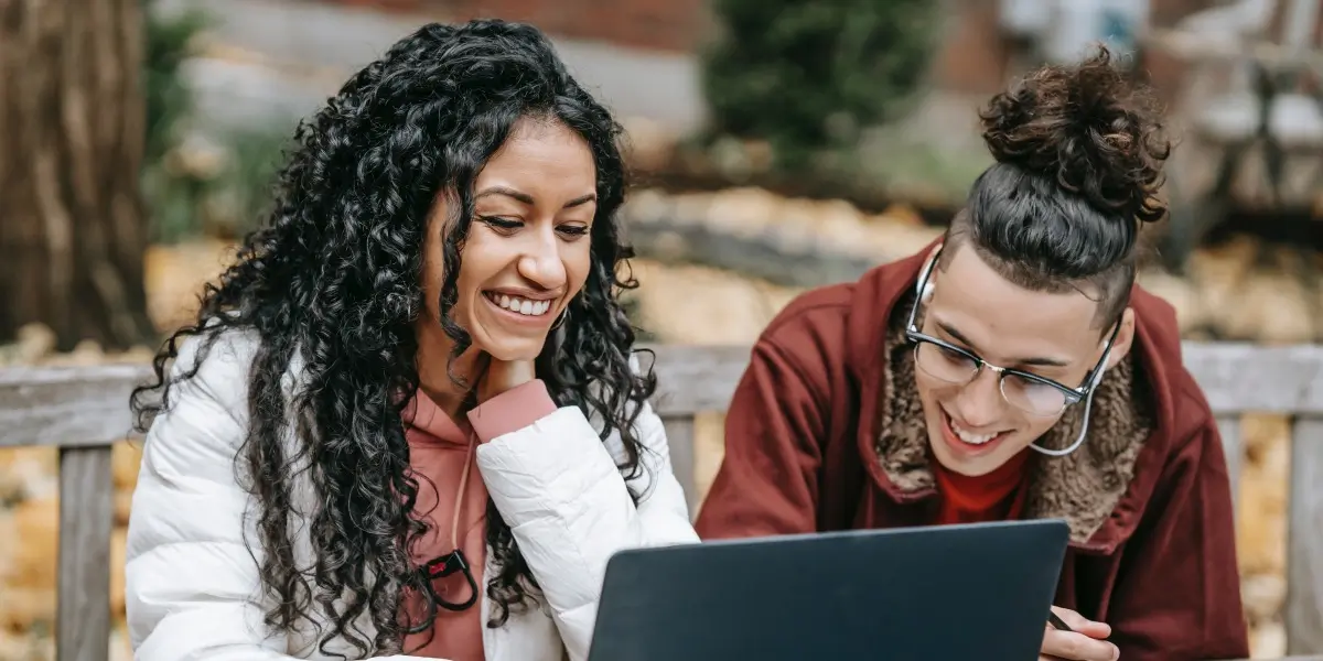 Two designers sitting in a park and working at a laptop