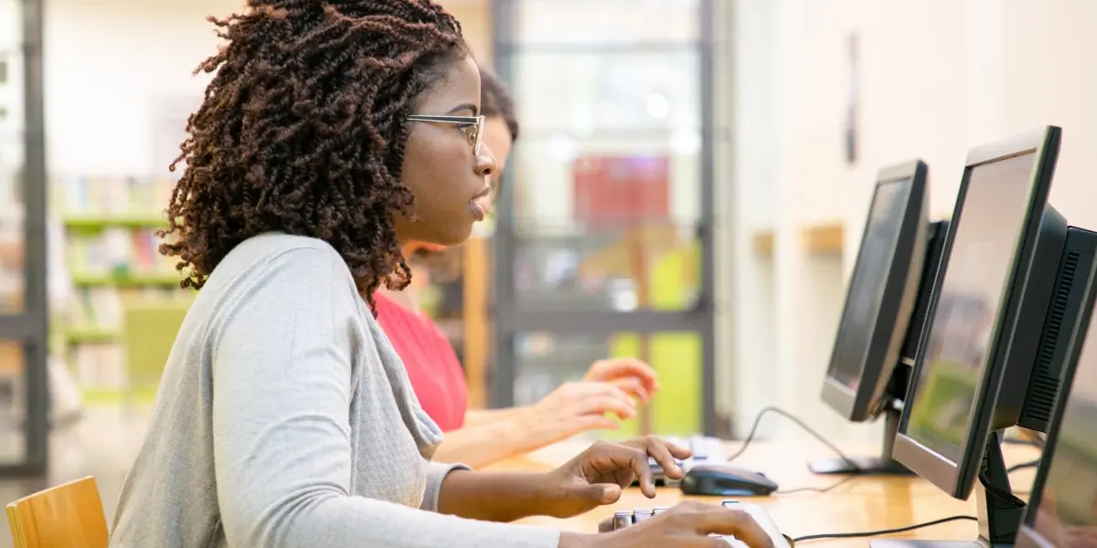 A woman sits at a computer learning an easiest programming languages