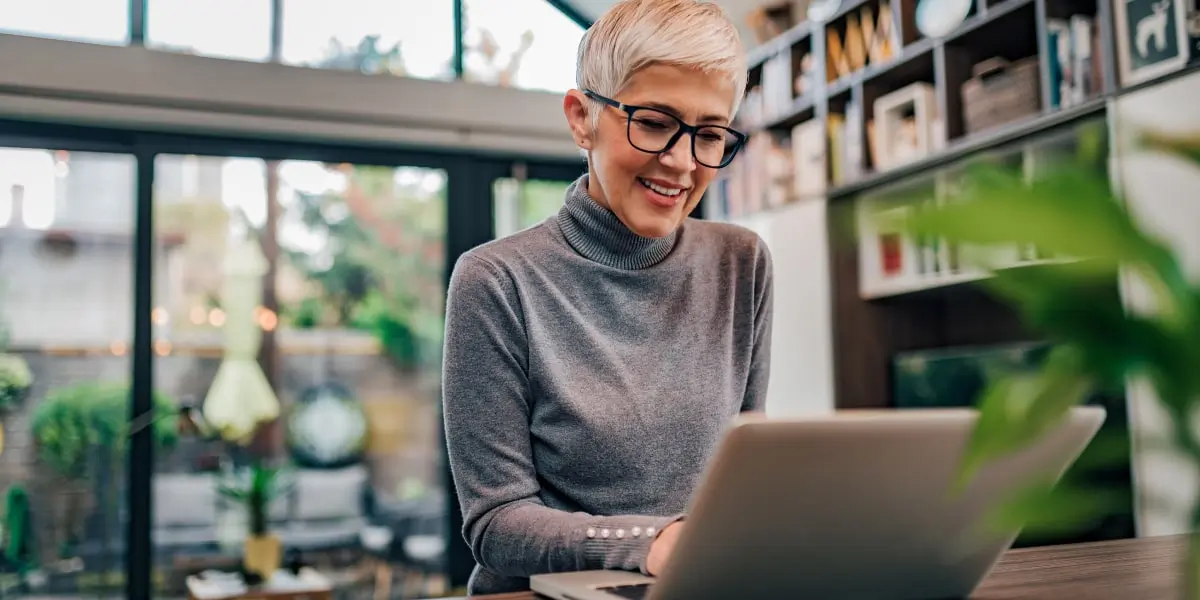 Digital marketing analyst salary by A digital marketing analyst sitting at a desk, looking at a laptop, smiling slightly