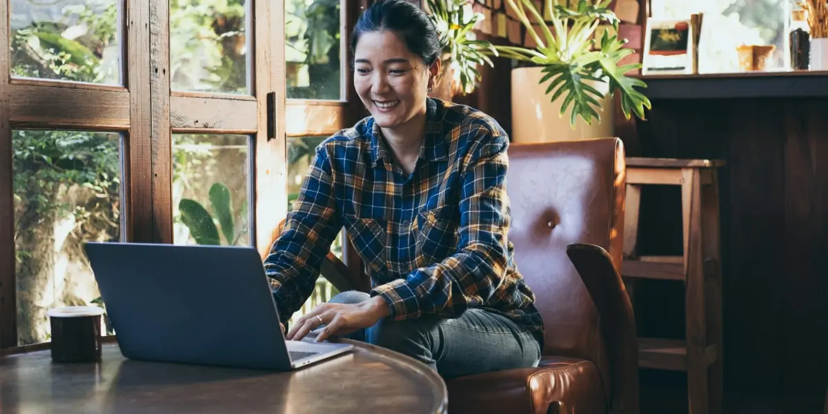 A digital marketing student sitting in a cafe working on a laptop