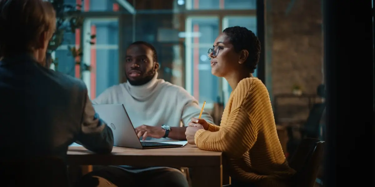 Three members of the tech team of a startup sit at a table studying examples of Python in web development.