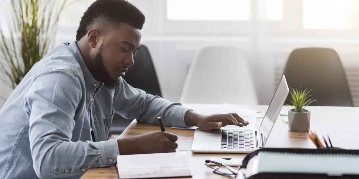 A marketing professional sitting at a desk in side profile, working on a laptop