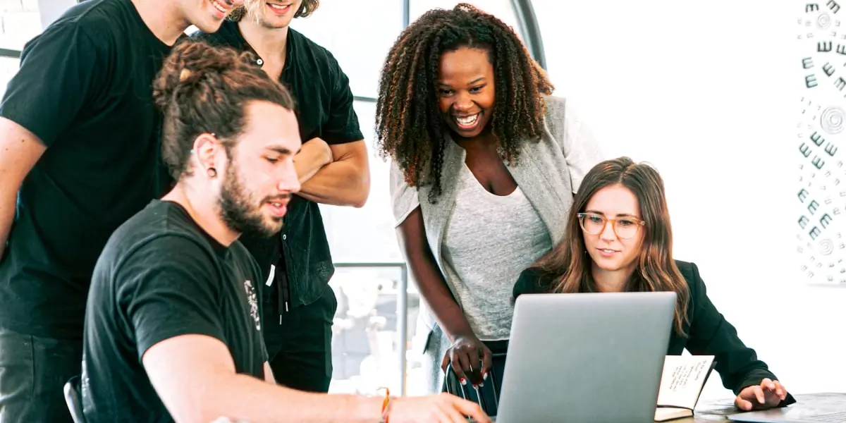 A UX design team gathered around a laptop 
