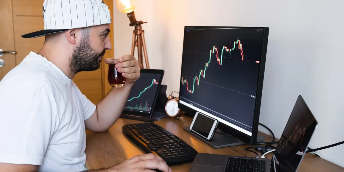 Digital marketing analyst guide A digital marketing analyst in side profile, sipping a cup of coffee and looking at a graph on a computer screen