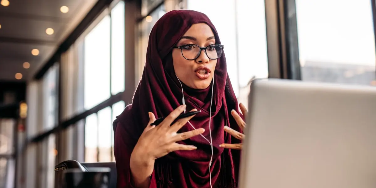 A digital marketing analyst wearing headphones, having a video call with a laptop