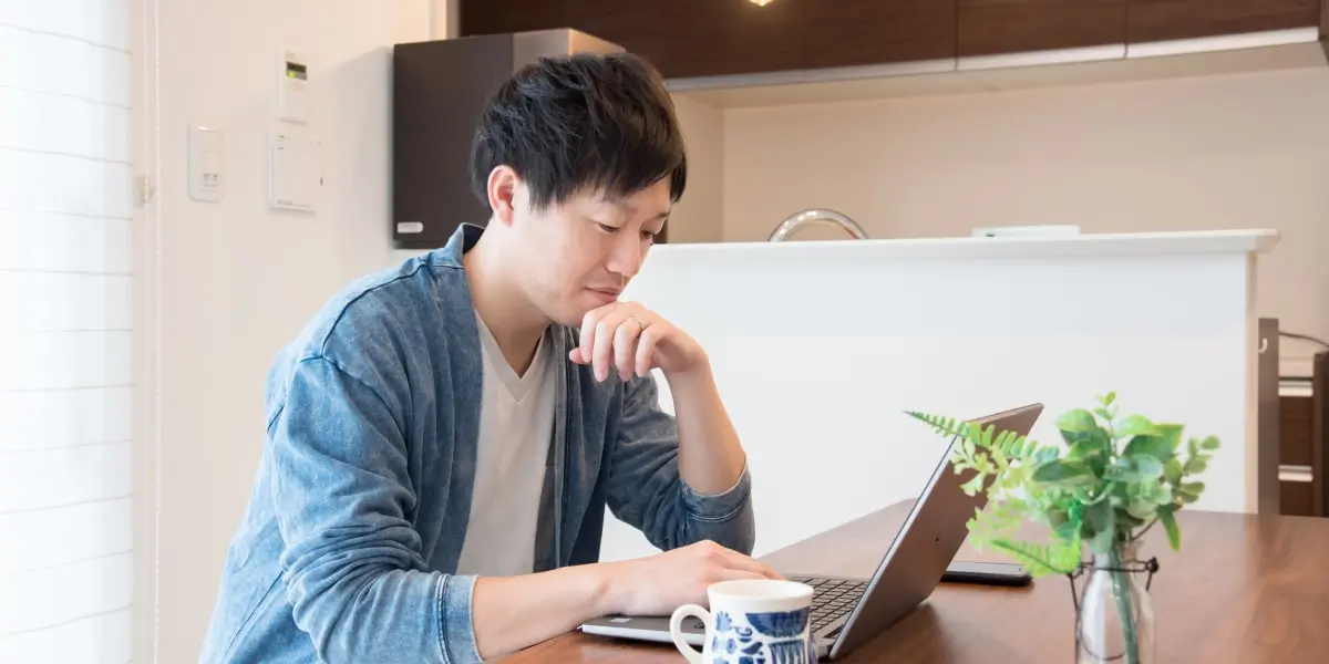 A social media manager sitting at a kitchen table, working on a laptop