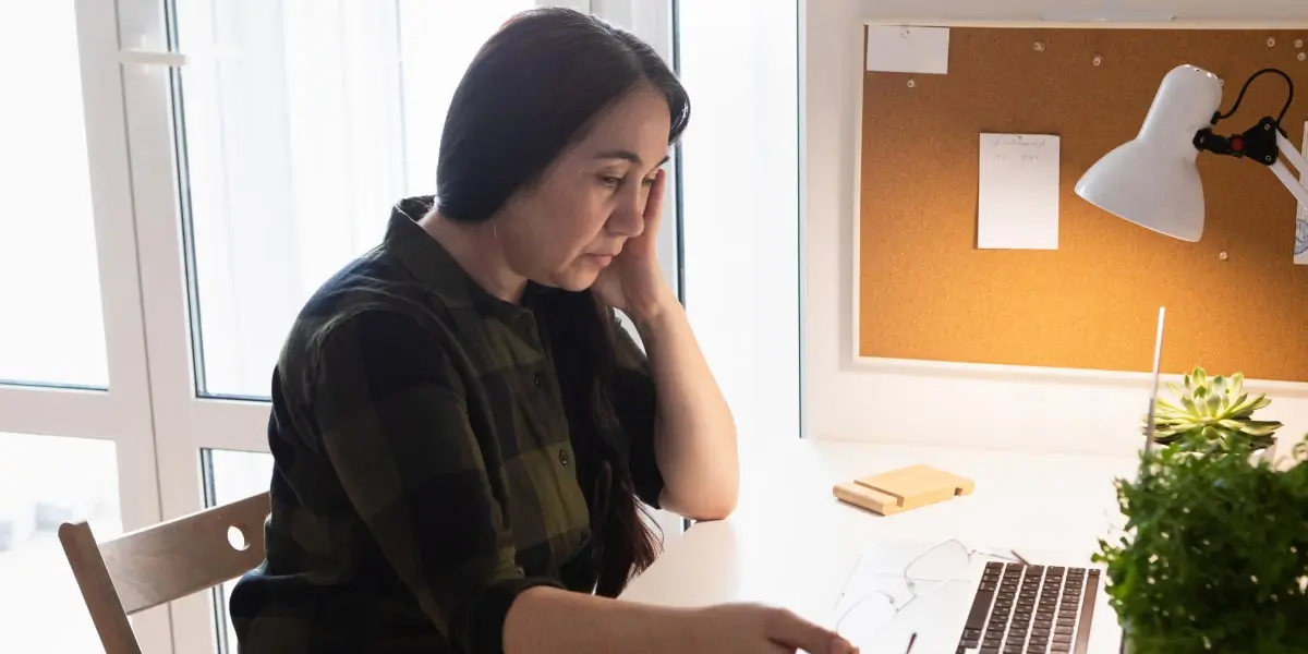 An aspiring social media manager in side profile, sitting at a desk looking at a laptop
