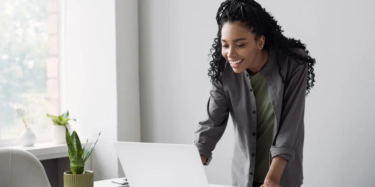 Marketing automation A digital marketer standing in front of a desk, leaning down to type on a laptop