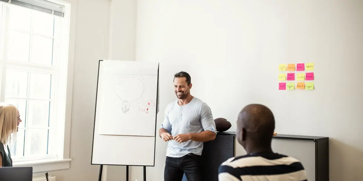 A team of UX designers in an office, one standing in front of a flipboard