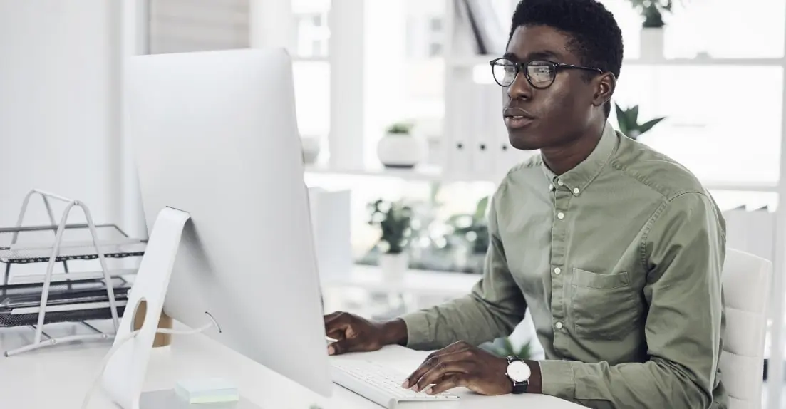 A UX designer sitting at a desk, working on a desktop computer