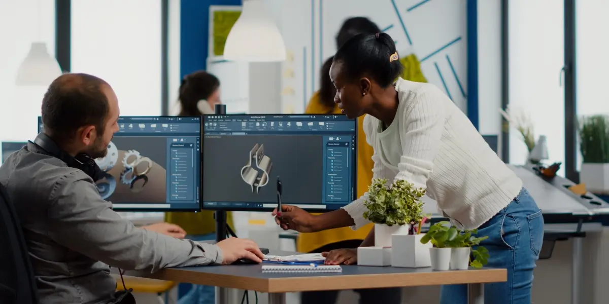 A product manager consults with their colleague at his desk in an office.