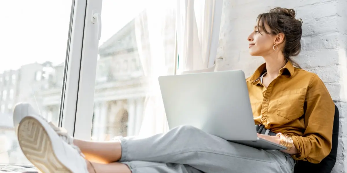 A woman sits at home on her laptop doing a full-stack developer certification online course.