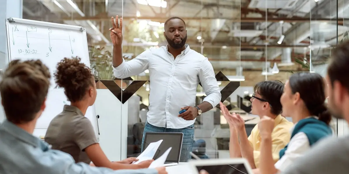 A team of designers get together in an office to solve wicked problems using a whiteboard and laptops.