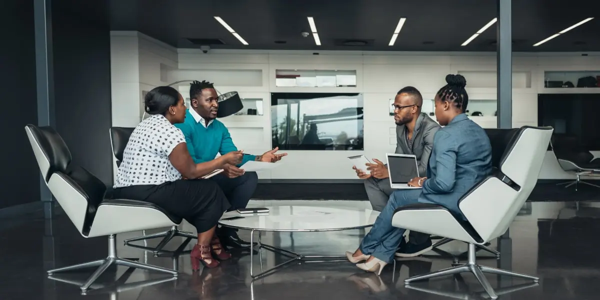 Product owner at a meeting with three other stakeholders in a modern office.