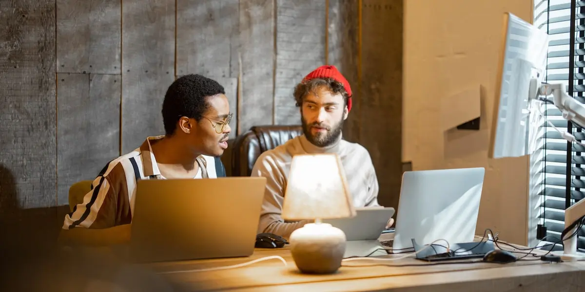 Two software engineers pair programming with a laptop in a coding course.