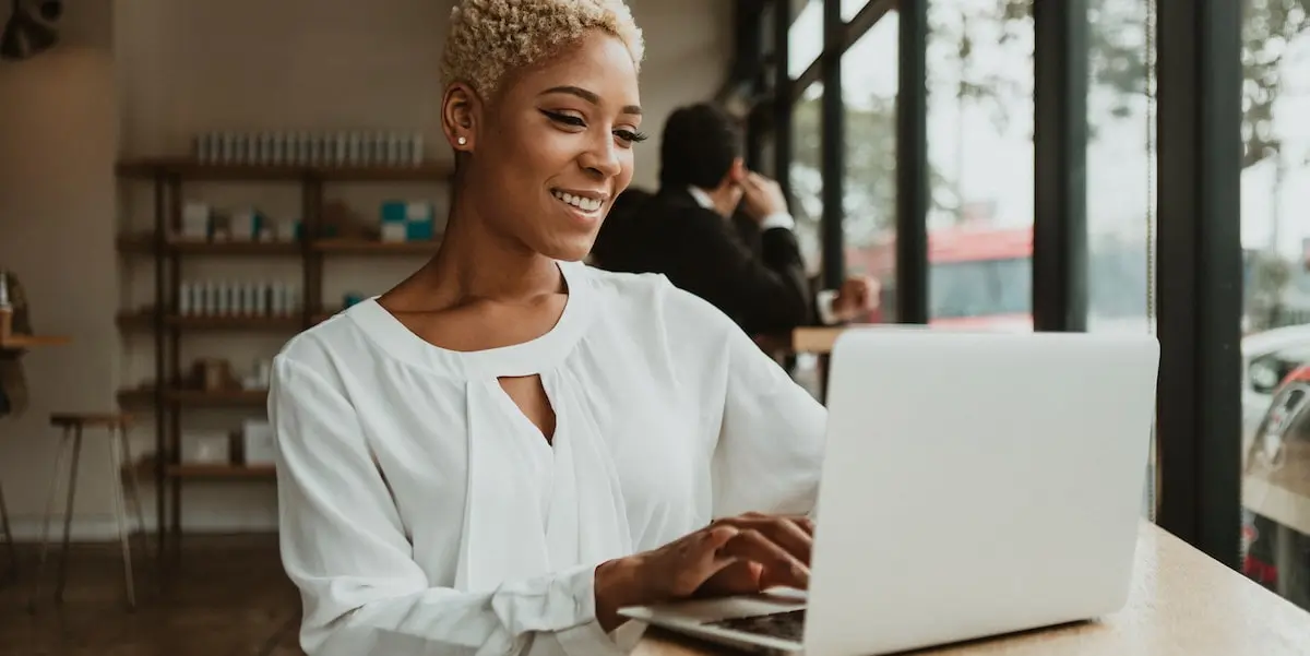 Woman works on her product manager resume in a coworking space on a laptop.