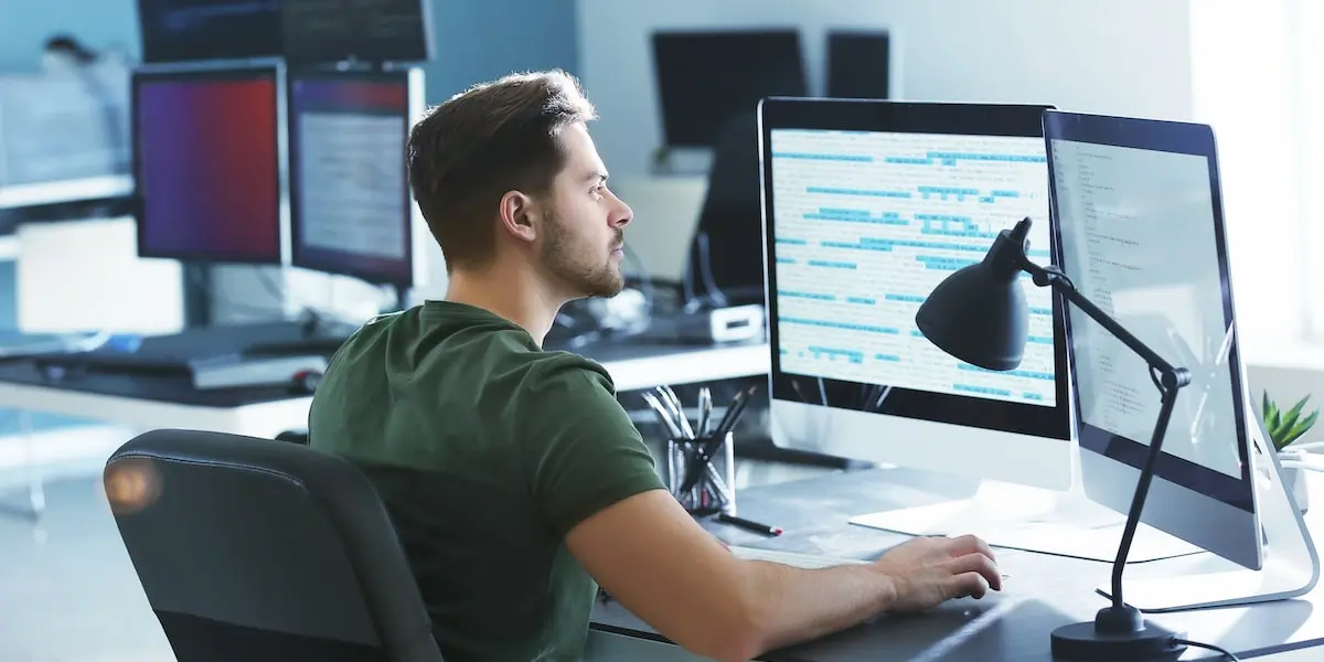 becoming a backend developer can start with the frontend A backend developer sits in a coworking space with two computer screens in front of him.
