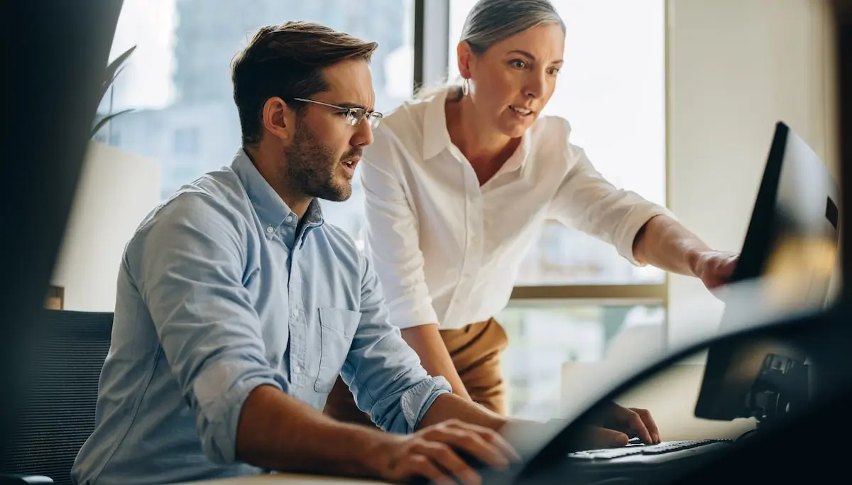 establishing regular processes is the key to good aws security A cloud engineer shows some AWS security protocols to her colleague at his office desk.