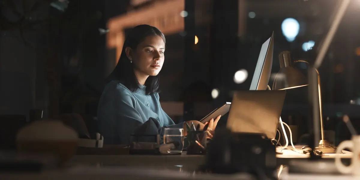 overworked young employee works overtime late at night thinking "I hate my job"