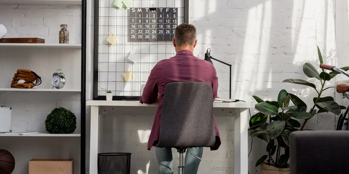 A man sits in his home office learning about product manager responsibilities on his computer.