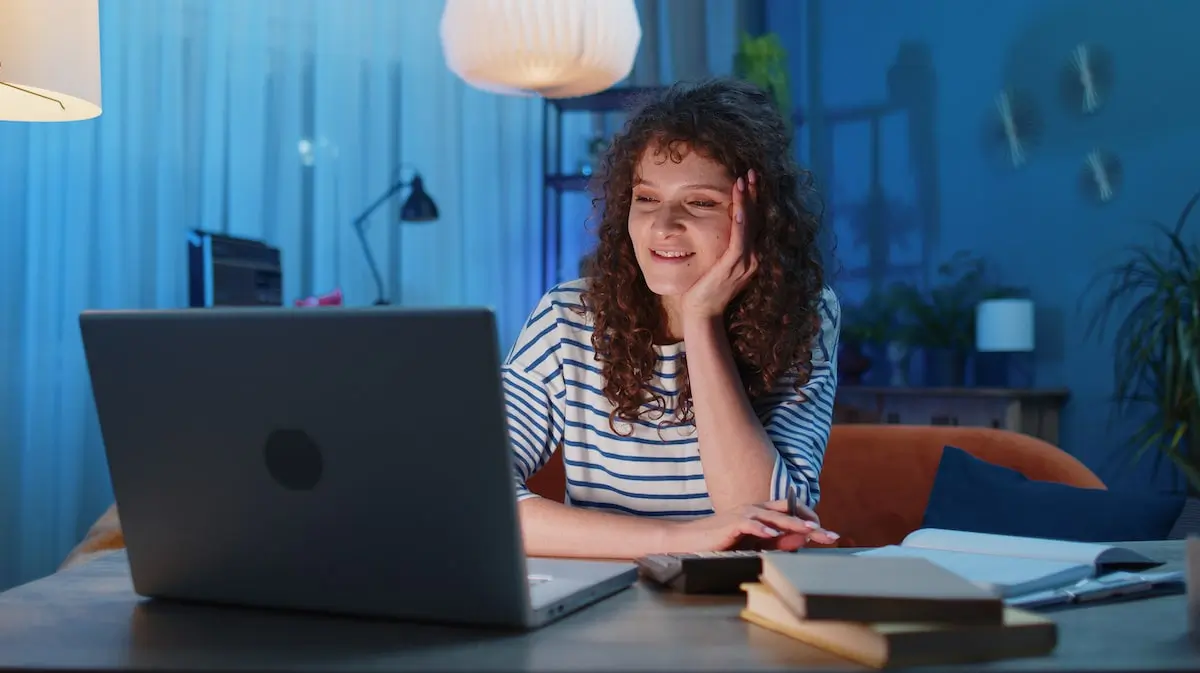 A woman sits in her home office at her computer screen.