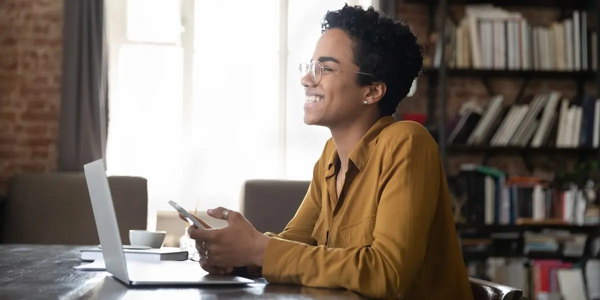 A freelance Node developer sits at her laptop in her home office smiling.