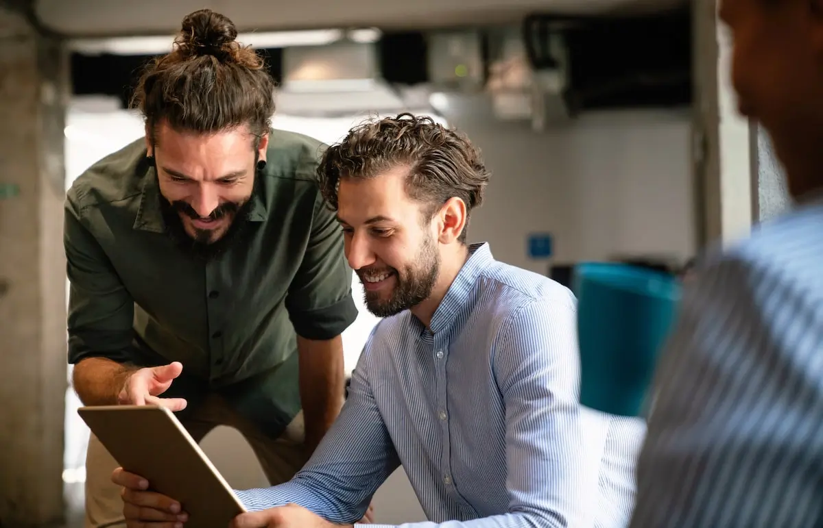 learning to apply WSJF is a key goal for product managers A product manager discusses a task with a tea member on a tablet.