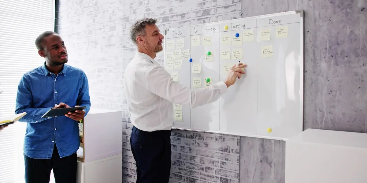 A scrum master moves tasks on the scrum team's Kanban board in the office.