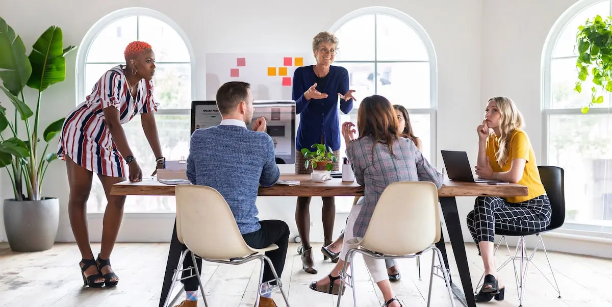 A product marketing manager leading a meeting in a bright office.
