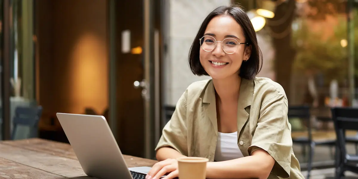 A digital marketer sits outside doing freelance work at a laptop