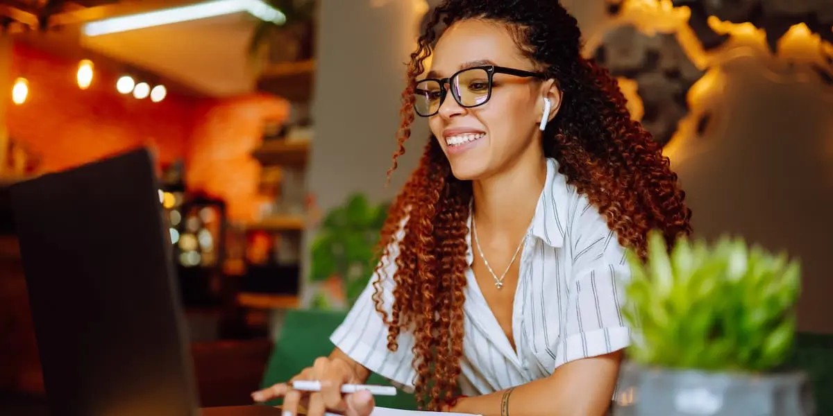 a young female-presenting employee working remotely in a restaurant with an expression that shows she loves her job