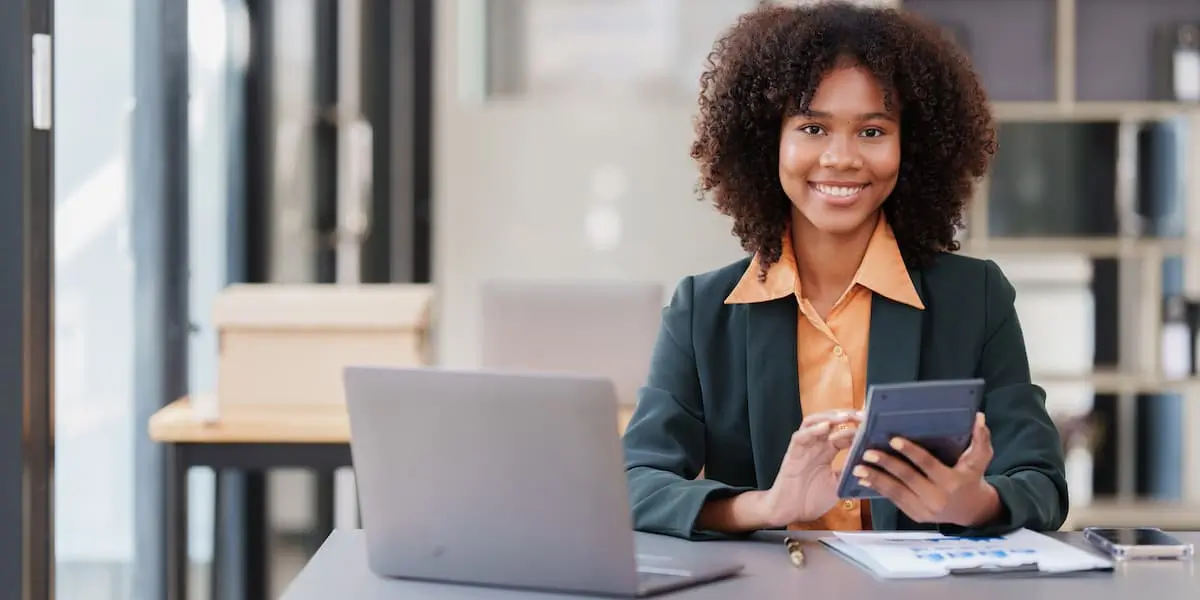 A young woman next to a laptop with a calculator works out how much a ux designer salary is in New York