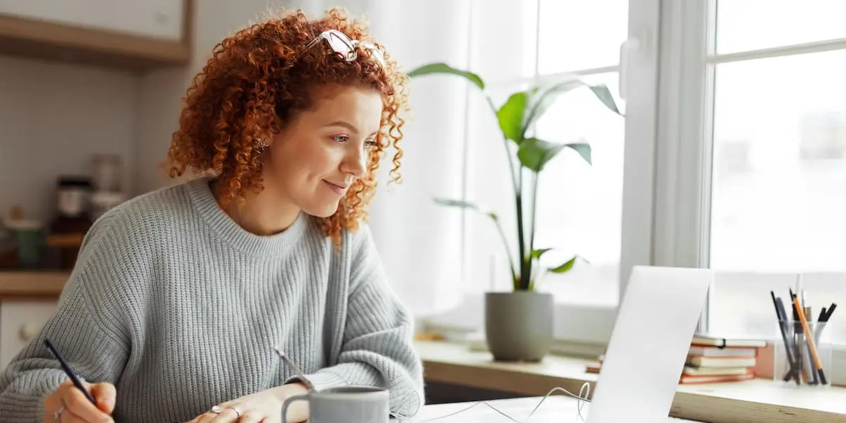 A young hybrid worker sits at her laptop at home talking to a colleague via the internet