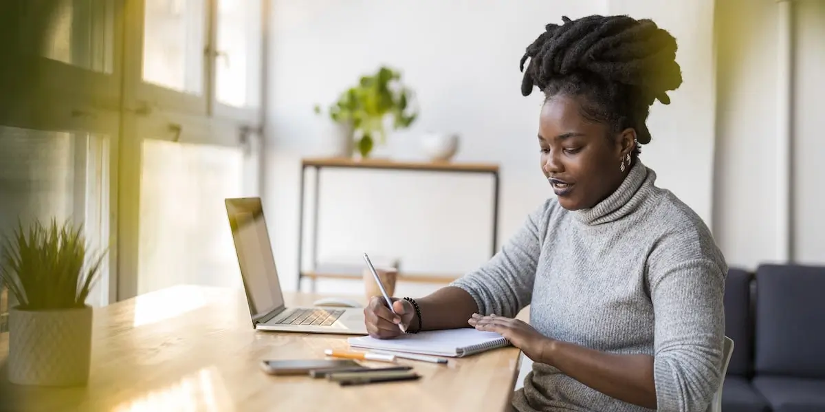 A woman sits applying predictive analytics on her laptop in a bright space.