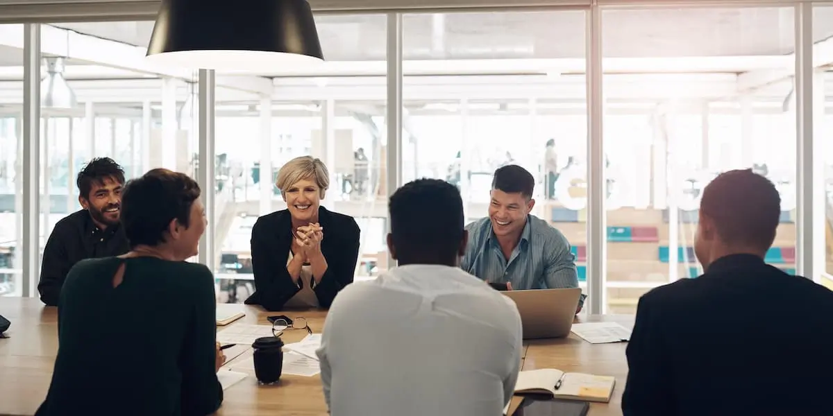 A team of tech workers laughing in a meeting room.