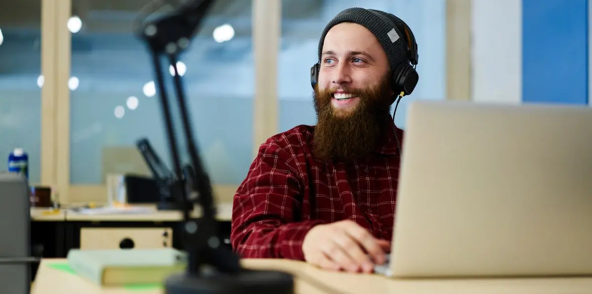 ai project ideas can apply to pretty much anything A man with a hat and headphone enjoys working with AI project ideas on a laptop.