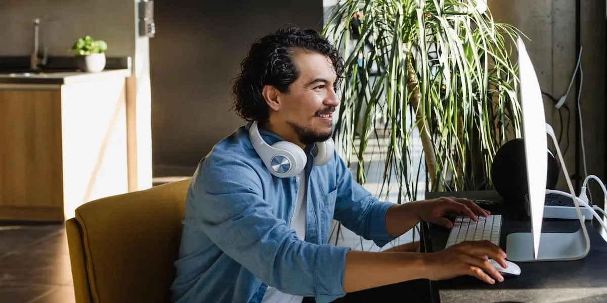 A man earning a product designer salary works away at a desktop computer at home.