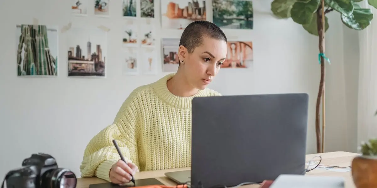 A product designer working at her laptop using a tablet to draw