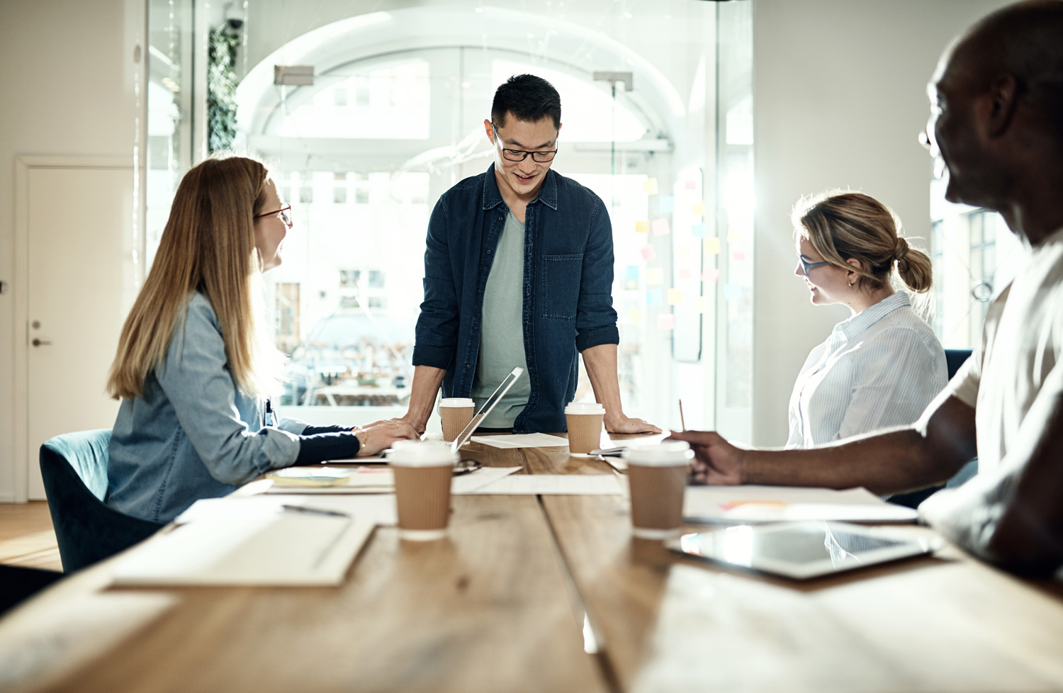 What is Quantitative UX Research? UX researchers seated at a table. One is standing to present research findings