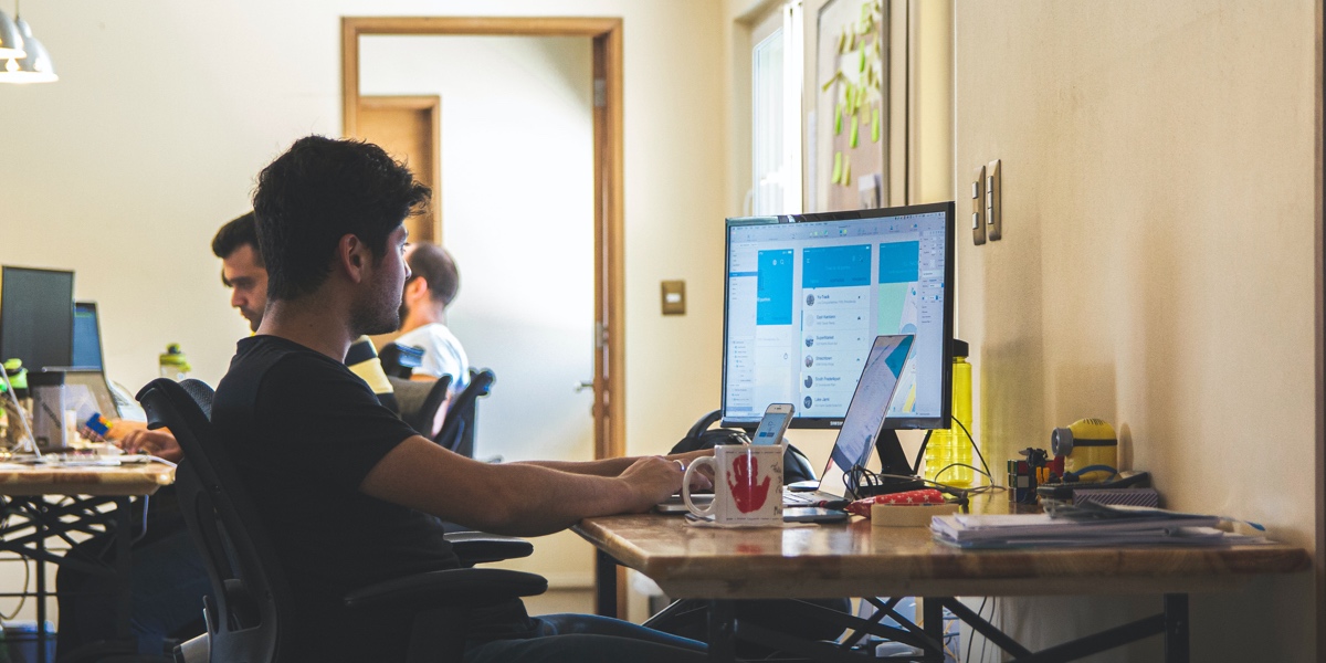 Break into Tech: How to Face Your Career Change Fears A man sitting at a desk, working on a computer in an open office